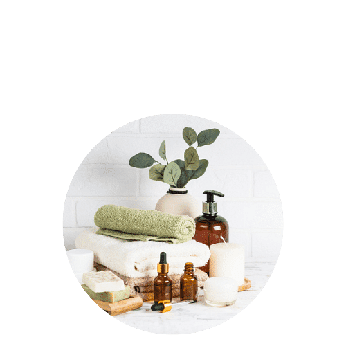 Spa essentials including towels, candles, and plant decor on a marble counter against a white wall.