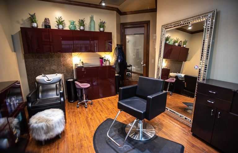 Modern salon with styling chair, large mirror, and hair washing station in a cozy setting.